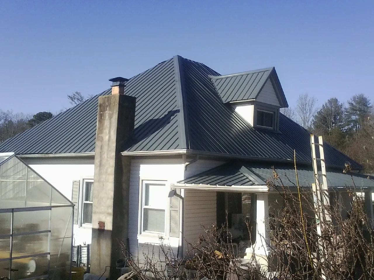 Dark blue standing seam metal roof on a white farmhouse with dormer — Slate & Tile Roof Repair by Roofing Brothers in Neptune