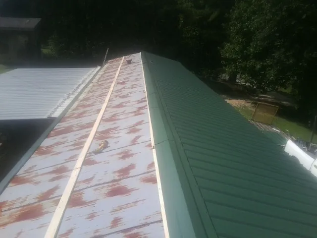 Old rusted panels beside newly installed green metal roofing — Wind Damage Roof Repair by Roofing Brothers in Neptune