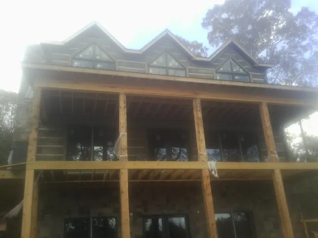 Dormers and porch framing on a large log home under construction — Roof Coating work by our crew in Neptune