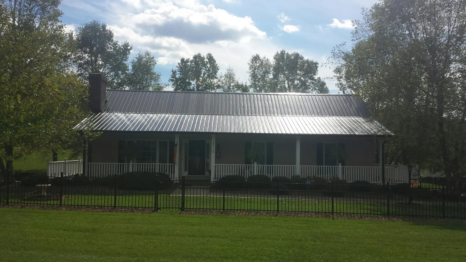 Gray metal roof on a brick ranch with a full width front porch — Gutter Guard Installation work by our crew in Neptune