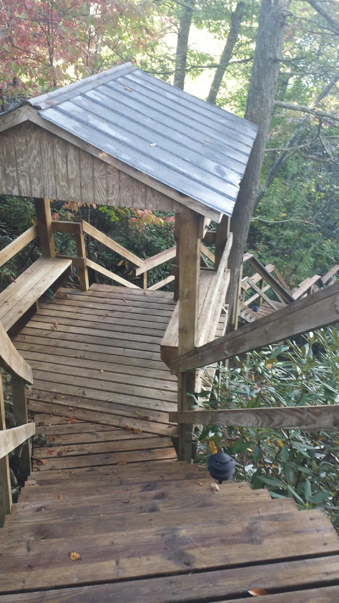 Metal roofed shelter over wooden steps on a wooded walkway — Skylight Repair & Installation work by our crew in Neptune
