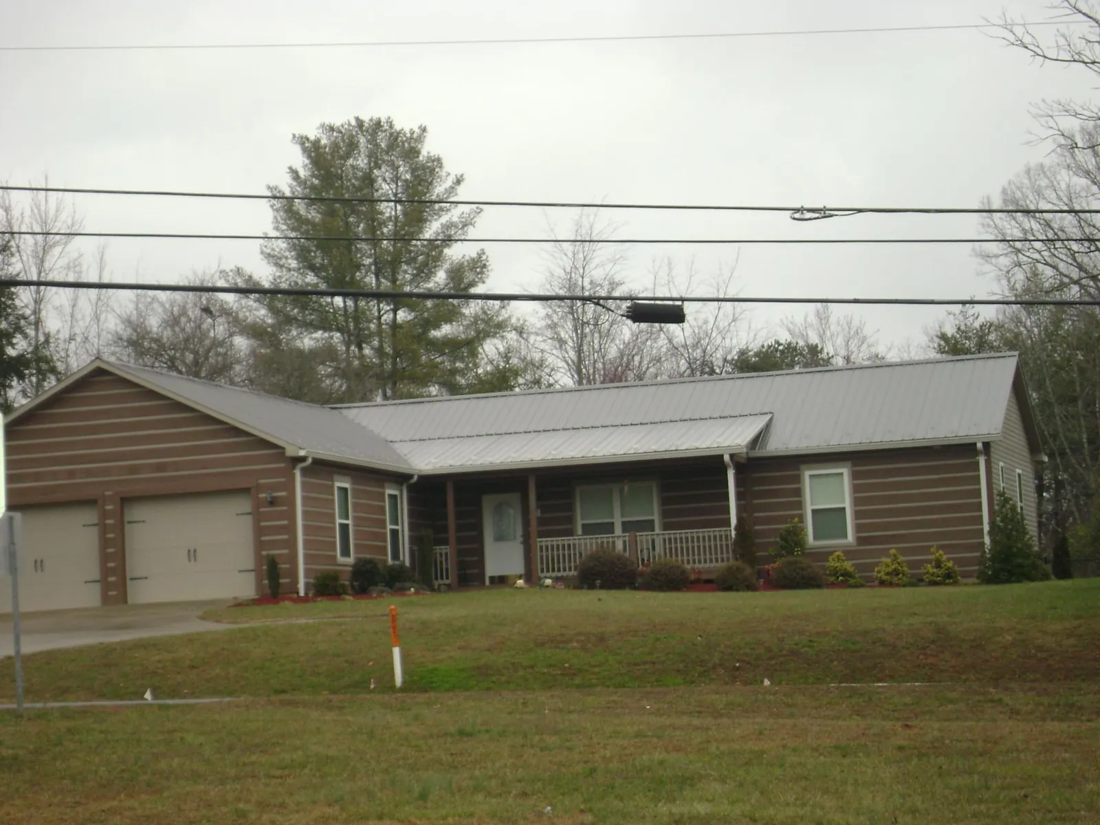 Gray metal roof on a log sided ranch home with a front porch in Neptune