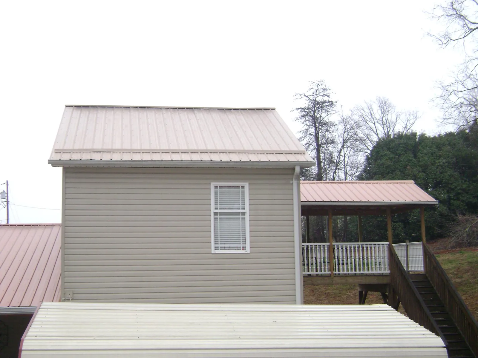 Tan metal roofs on a two story addition and attached porch, from a Roof Replacement job in Neptune