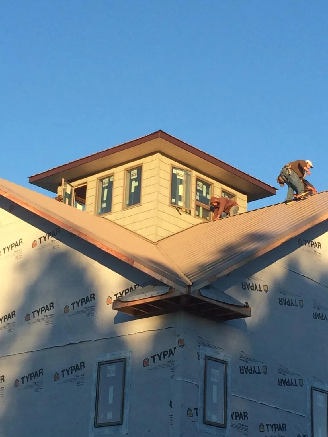 Roofers working around a rooftop cupola on a new metal roof at sunset — Roof Waterproofing in Neptune by Roofing Brothers